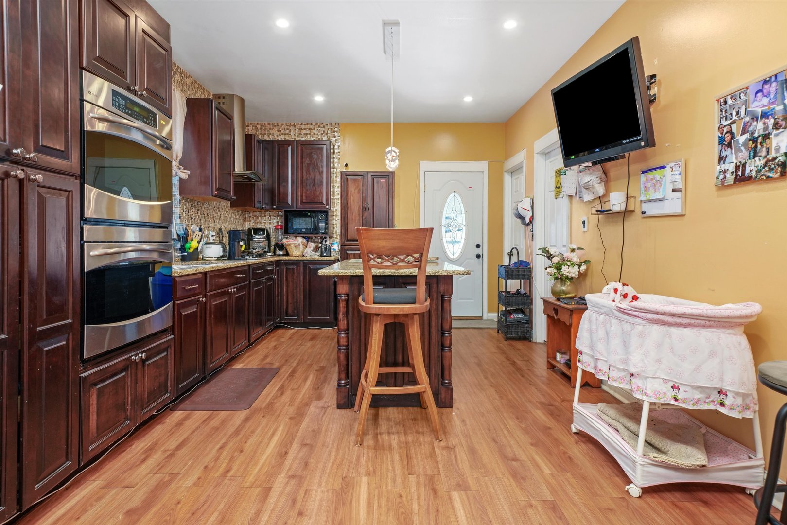 Undisclosed Address Chicago, IL 60641 - Photo 7 of 32 a kitchen with stainless steel appliances kitchen island granite countertop a stove top oven a sink a dining table and chairs with wooden floor