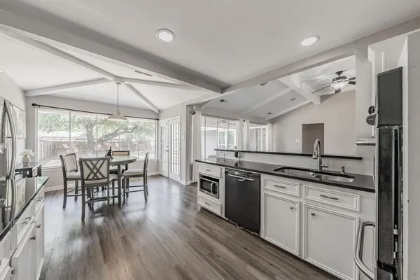 a kitchen with stainless steel appliances granite countertop hardwood floor sink stove dining table and chairs