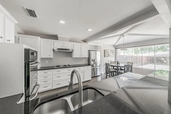 a kitchen with granite countertop white cabinets and stainless steel appliances