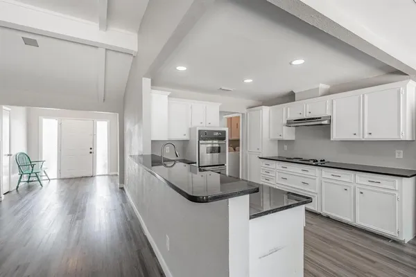 a large kitchen with stainless steel appliances lots of counter space and wooden floor