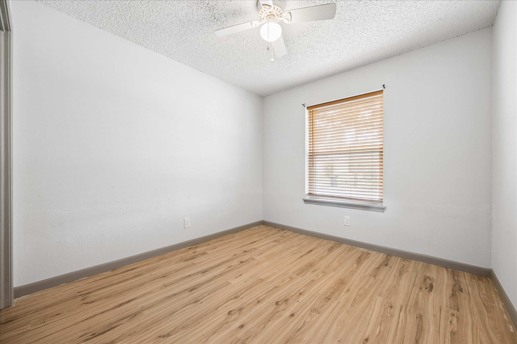206 Lockett Street Brenham, TX 77833 - Photo 10 of 12 an empty room with wooden floor chandelier fan and windows