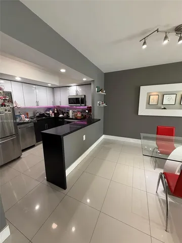 a kitchen with stainless steel appliances a sink a stove a refrigerator cabinets and dining table