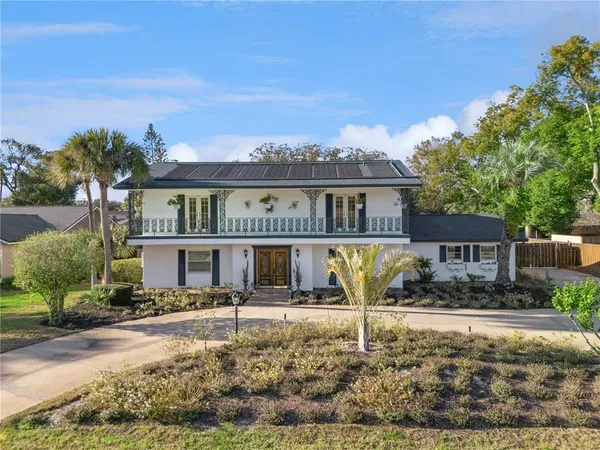 a front view of a house with large trees
