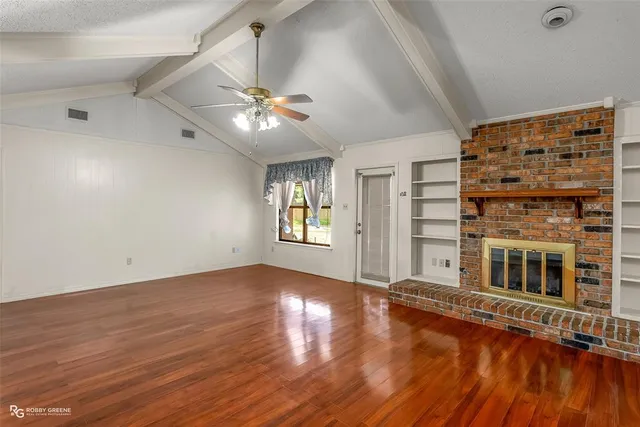 a view of an empty room with window and wooden floor