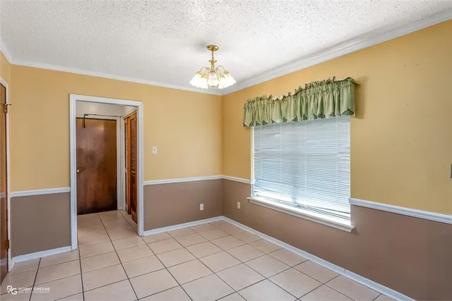 a view of an empty room with window and chandelier fan