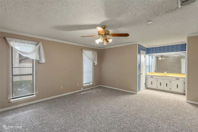 a view of an empty room with window and a kitchen view