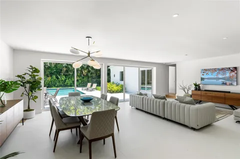 a kitchen with stainless steel appliances granite countertop a stove top oven a sink dishwasher a dining table and chairs with wooden floor