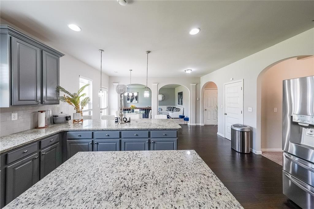 8097 White Oak Loop Lithonia, GA 30038 - Photo 14 of 25 a large kitchen with stainless steel appliances kitchen island granite countertop a large island in the center