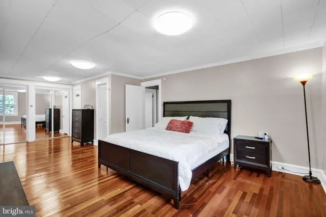 a spacious bedroom with a bed and wooden floor