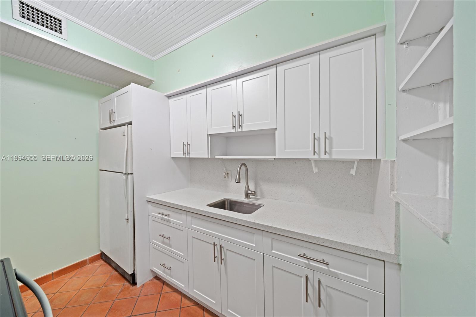 7110 Southwest 13th Terrace Miami, FL 33144 - Photo 12 of 39 a kitchen with white cabinets and a refrigerator