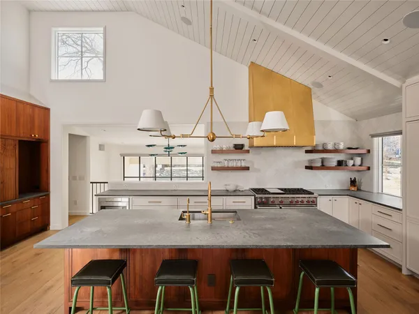 a kitchen with kitchen island granite countertop a table chairs stove and cabinets