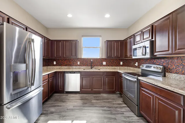 a kitchen with stainless steel appliances granite countertop a refrigerator a sink dishwasher a stove top oven and a refrigerator