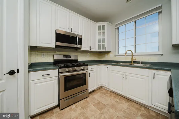 a kitchen with granite countertop white cabinets stainless steel appliances and a sink