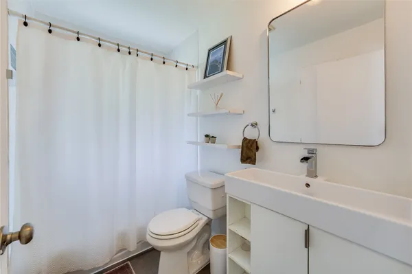 a bathroom with a sink a toilet and shower curtain