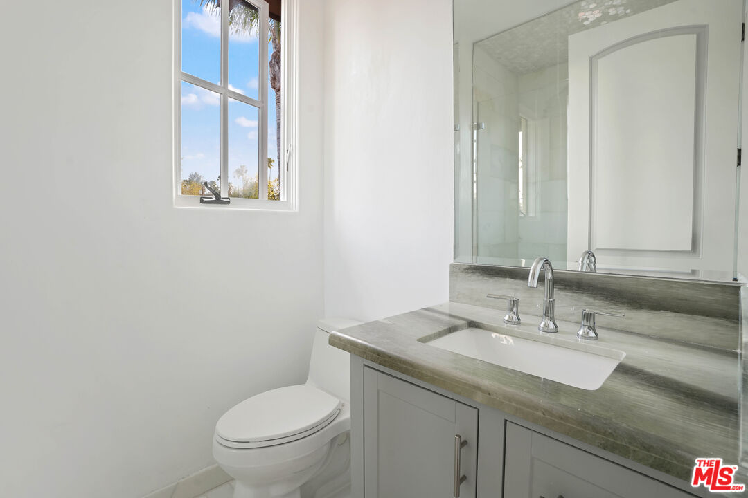5309 Louise Avenue Encino, CA 91316 - Photo 21 of 38 a bathroom with a granite countertop toilet a sink and mirror