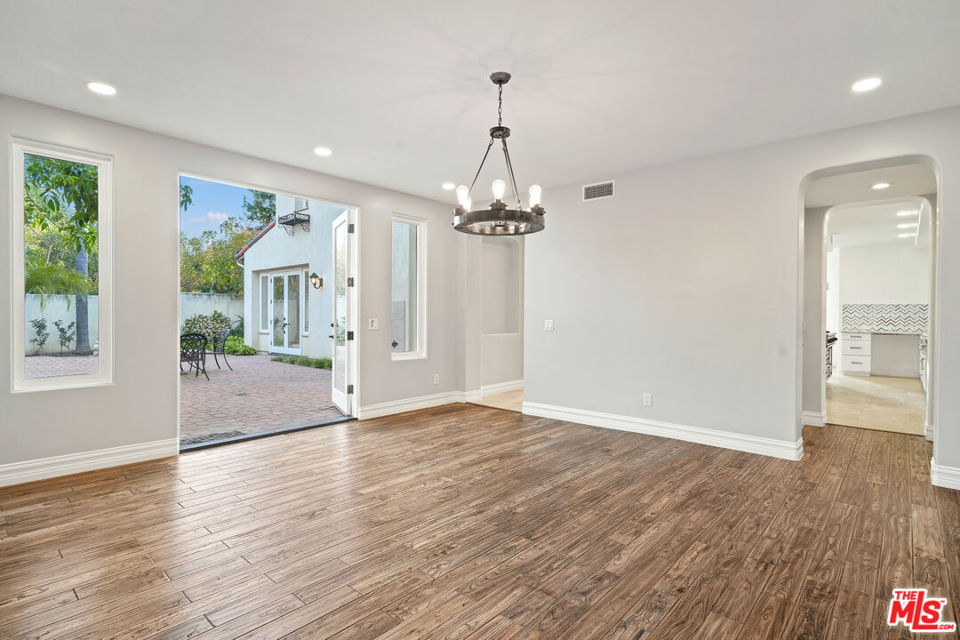5309 Louise Avenue Encino, CA 91316 - Photo 5 of 38 an empty room with wooden floor mirror and windows