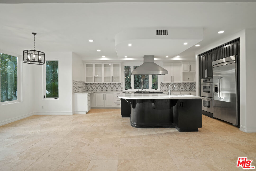 5309 Louise Avenue Encino, CA 91316 - Photo 10 of 38 a kitchen with kitchen island granite countertop wooden cabinets and a fireplace