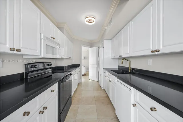 a kitchen with granite countertop a sink and white cabinets