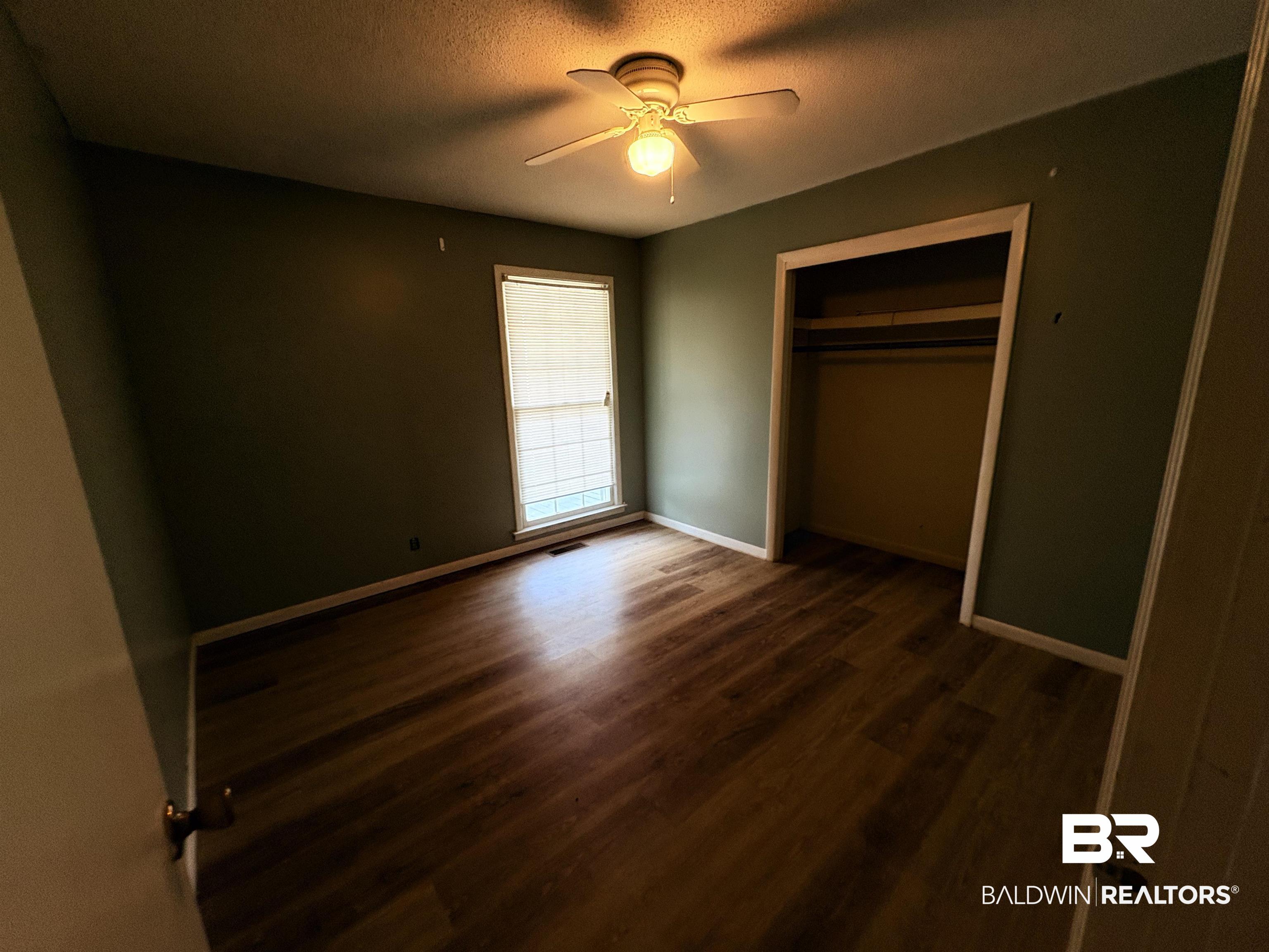 8065 Middle Ring Road Mobile, AL 36619 - Photo 8 of 21 Unfurnished bedroom with a closet, a textured ceiling, baseboards, and wood finished floors