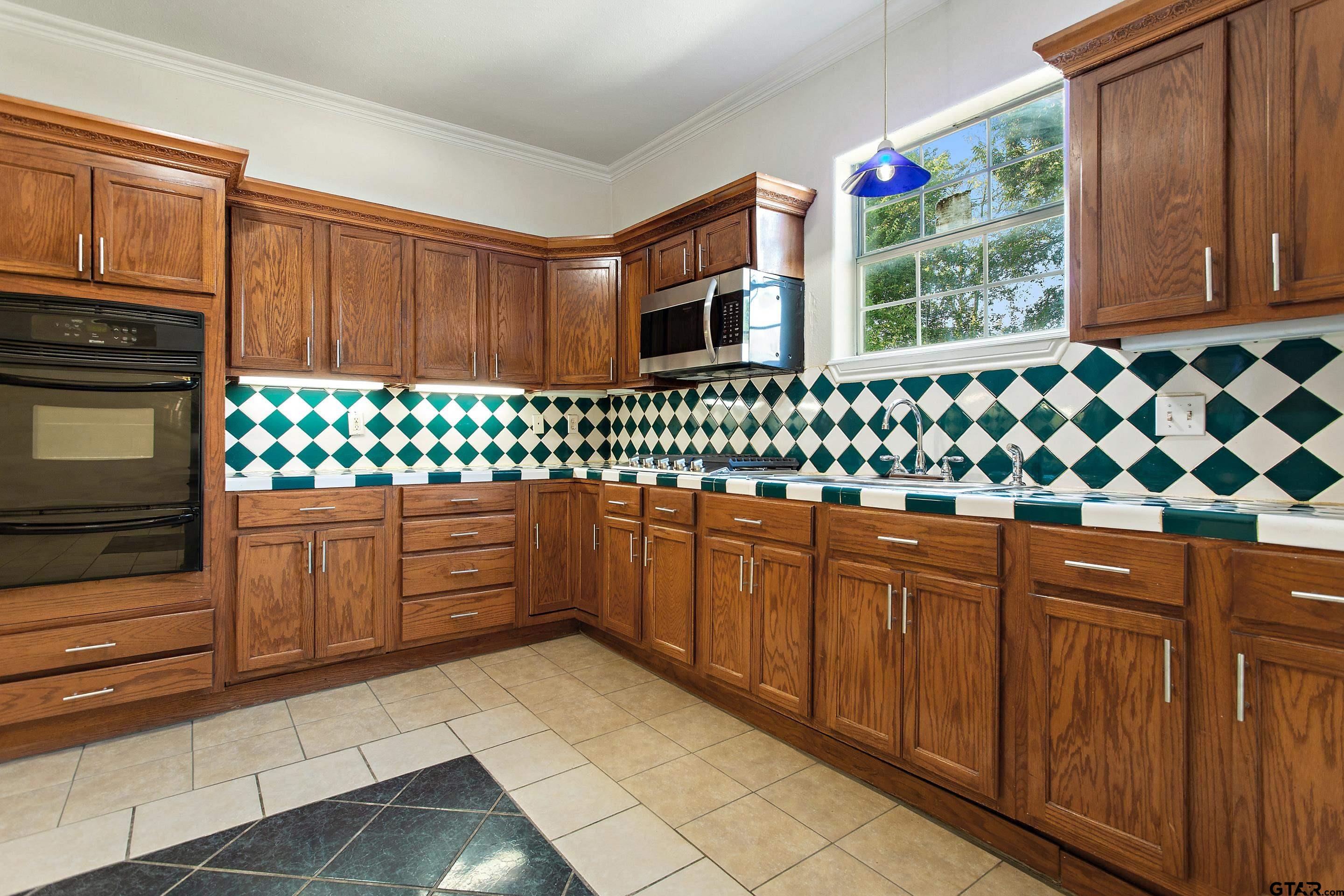 1002 North Normandy Avenue Tyler, TX 75702 - Photo 17 of 41 a kitchen with granite countertop white cabinets and window