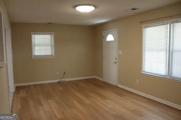 an empty room with wooden floor and windows