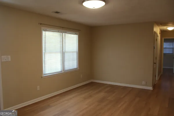 a view of an empty room with wooden floor and a window