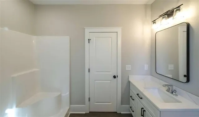 a bathroom with a tub sink vanity and mirror