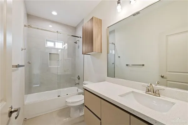 a bathroom with a granite countertop sink a toilet a shower and a mirror