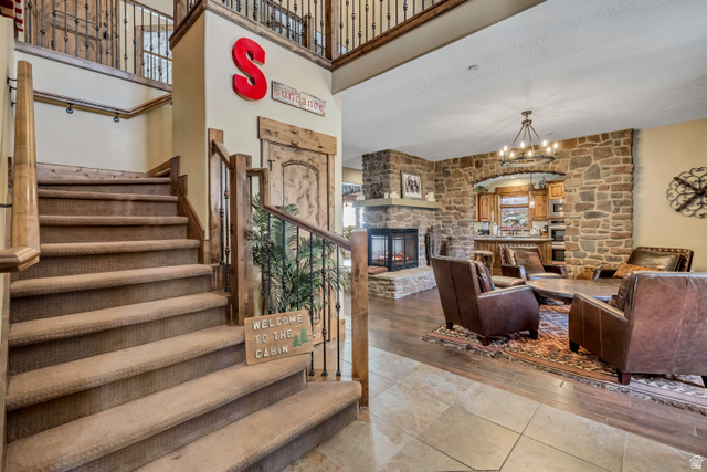 9049 Timphaven Road Sundance, UT 84604 - Photo 24 of 63 Stairs with a high ceiling, a stone fireplace, a chandelier, and wood finished floors