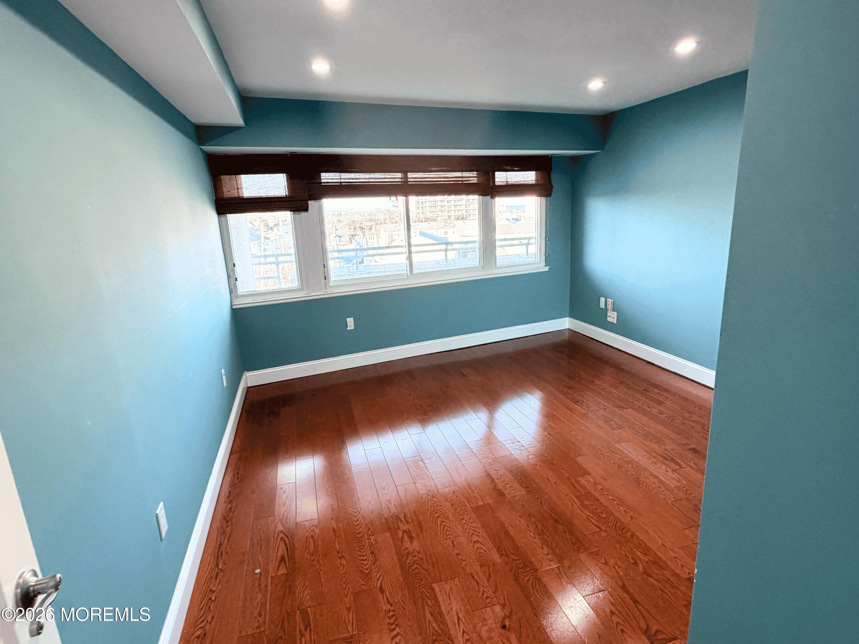 525 Ocean Boulevard, Unit 405 Long Branch, NJ 07740 - Photo 11 of 18 an empty room with wooden floor and windows