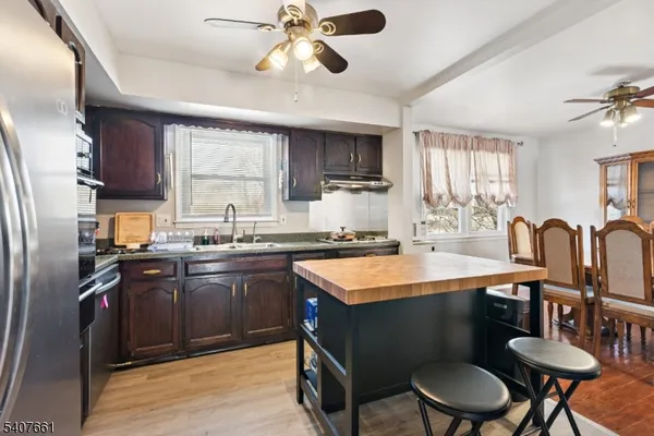 a kitchen with stainless steel appliances granite countertop a sink a stove a refrigerator cabinets and dining table
