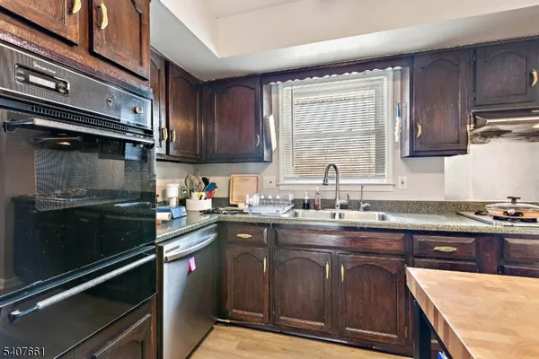 a kitchen with kitchen island granite countertop a sink cabinets stainless steel appliances and a window