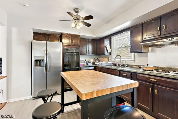 a kitchen with stainless steel appliances granite countertop a table chairs stove and refrigerator