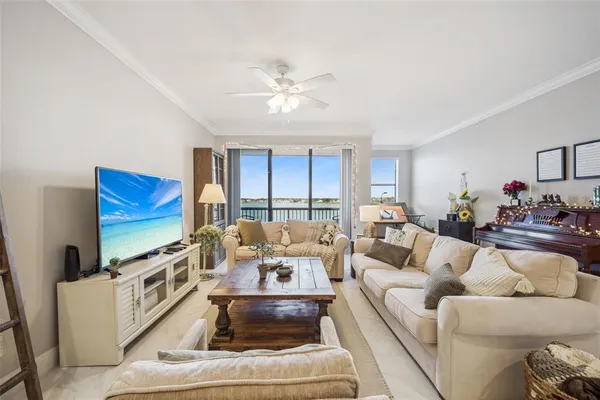 a living room with furniture flat screen tv and a ceiling fan