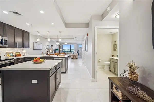 a kitchen with kitchen island stainless steel appliances a sink a stove top oven a counter space and cabinets