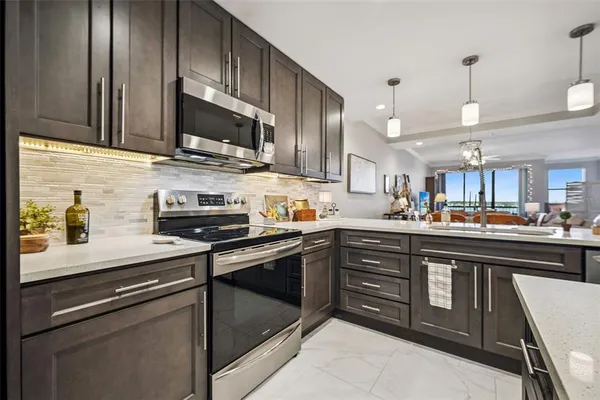 a kitchen with stainless steel appliances granite countertop wooden cabinets a sink a stove and a microwave