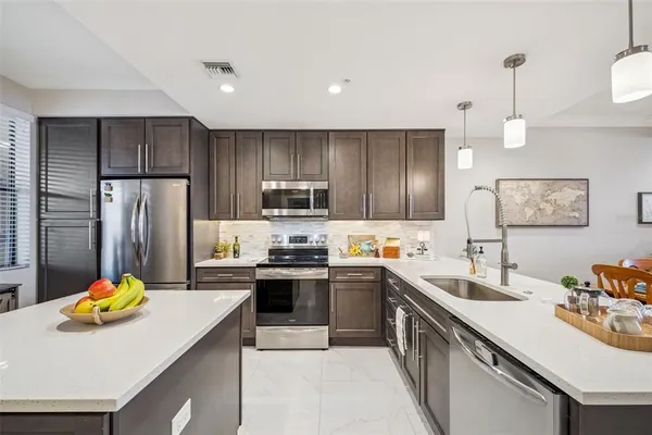 a kitchen with stainless steel appliances a sink a stove a refrigerator a center island and cabinets