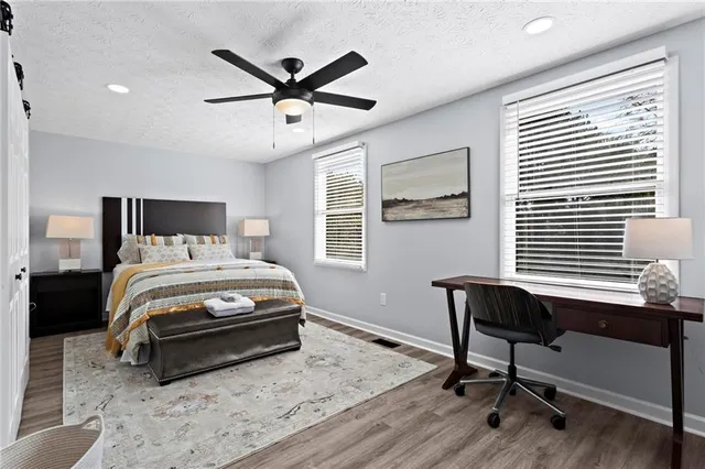 a bedroom with a bed a desk and chair with wooden floor