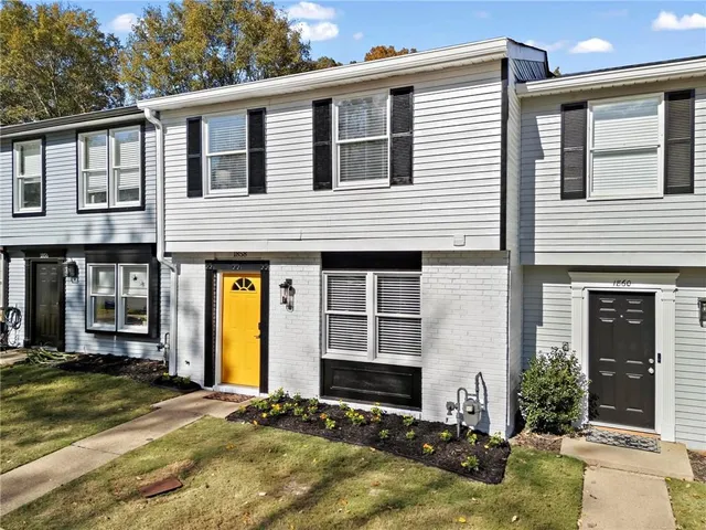 a view of a house with small yard plants and large tree