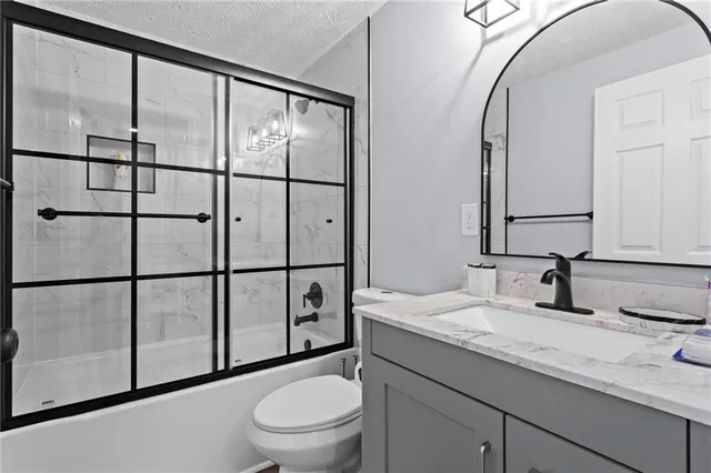 a bathroom with a granite countertop sink a toilet and a mirror