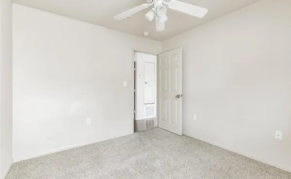 an empty room with a ceiling fan and a window