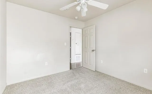 an empty room with a ceiling fan and a window