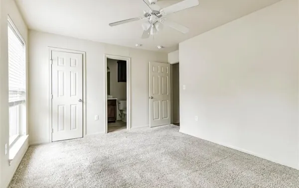 an empty room with a windows and chandelier fan