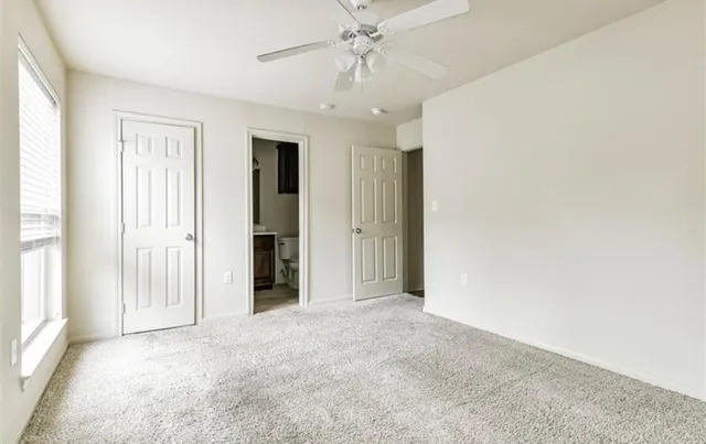 an empty room with a windows and chandelier fan