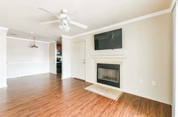 a view of an empty room with wooden floor fireplace and a window