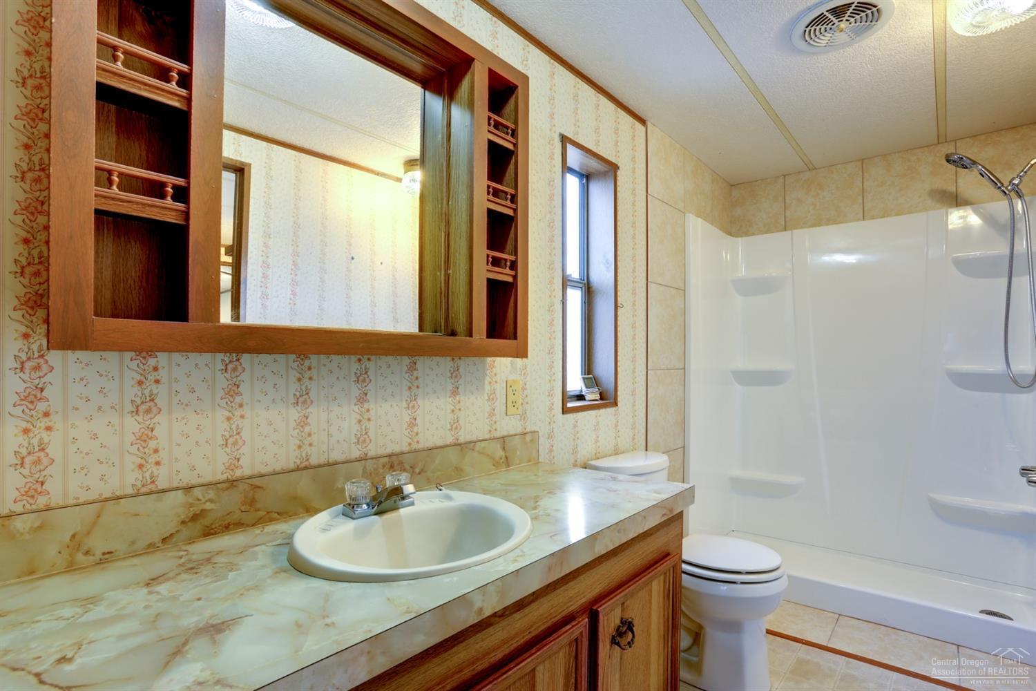 65040 Hunnell Road Bend, OR 97703 - Photo 7 of 25 a bathroom with a granite countertop sink toilet and a mirror