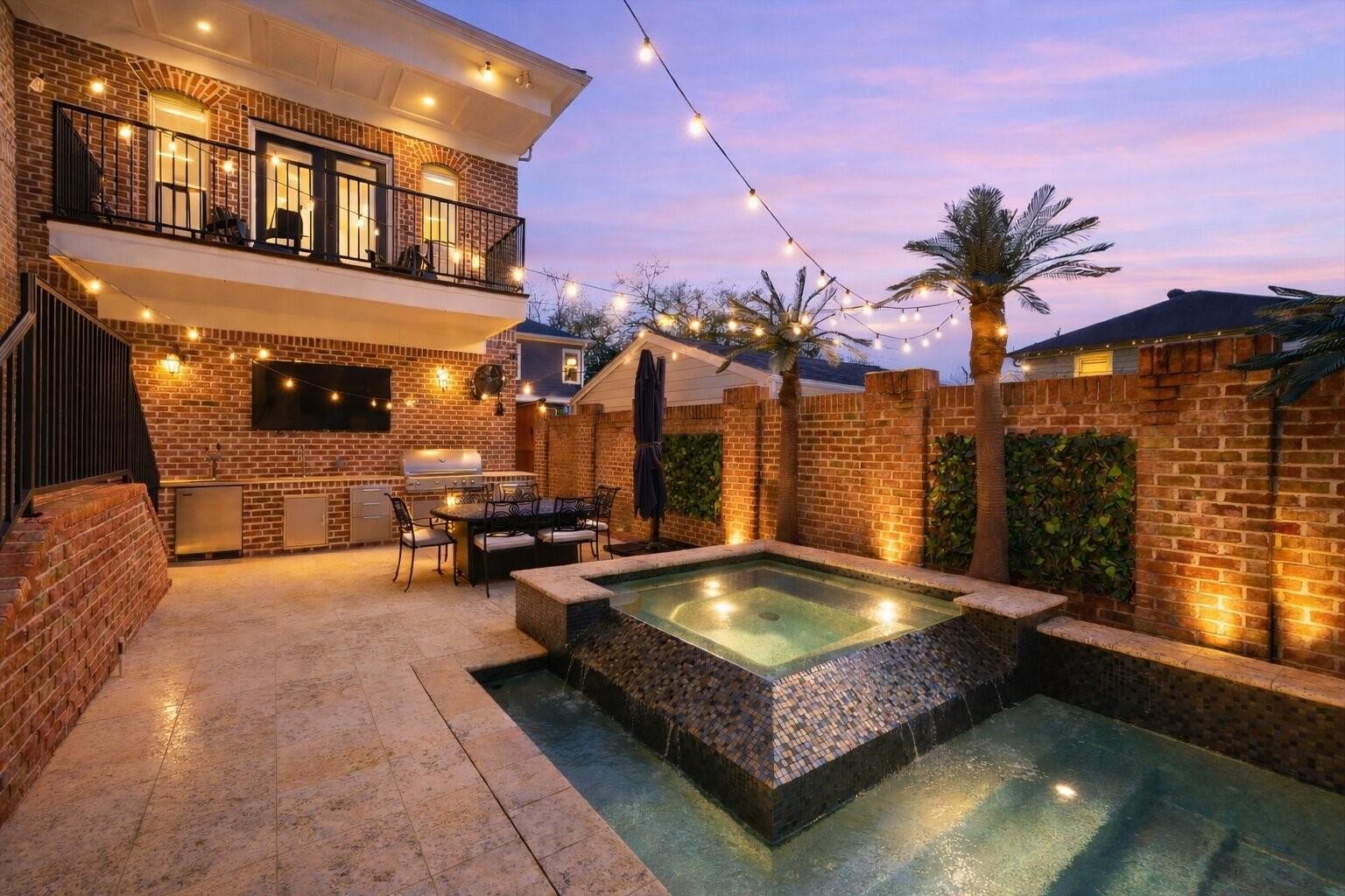 1418 Columbia Street Houston, TX 77008 - Photo 2 of 45 A backyard retreat designed for unforgettable evenings. Pool and spa with cascading water feature, summer kitchen (2022) with built-in grill, warming drawer, beer taps, TV, and café lights overhead creating the perfect setting