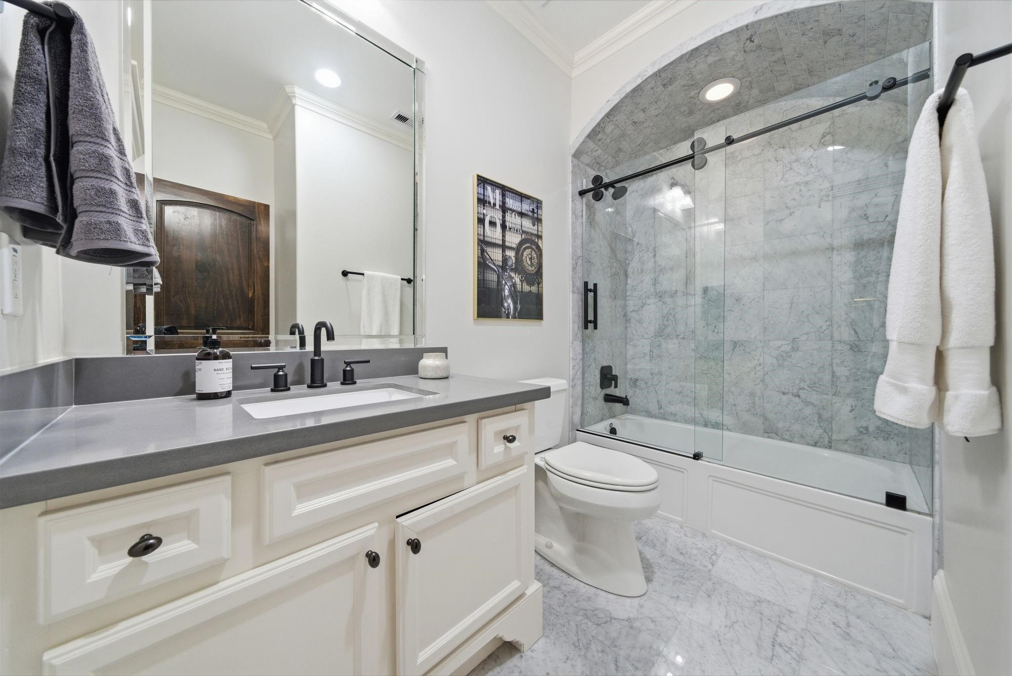 1418 Columbia Street Houston, TX 77008 - Photo 31 of 45 Serving the third floor suite, this bath was updated in 2021 and features quartz counters, marble tile, and a glass enclosed tub and shower highlighted by a beautiful arched ceiling that adds architectural charm.