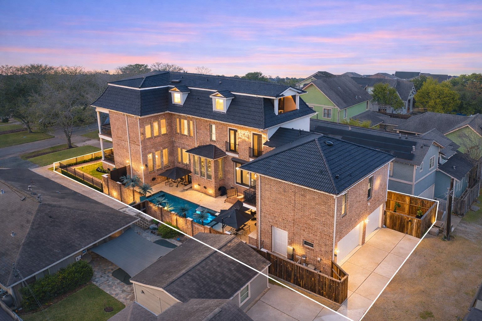 1418 Columbia Street Houston, TX 77008 - Photo 44 of 48 A striking all-brick residence designed for living at scale, glowing at sunset with balconies overlooking the pool, multiple outdoor spaces, a rare three-car garage with alley access, and a custom black metal shingle roof (2025) for lasting style and durability.