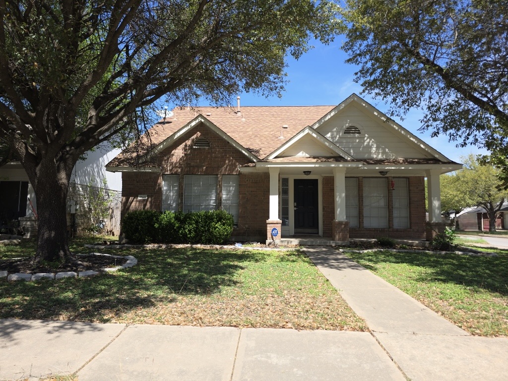 View of front of house featuring covered porch, a front lawn, and brick siding